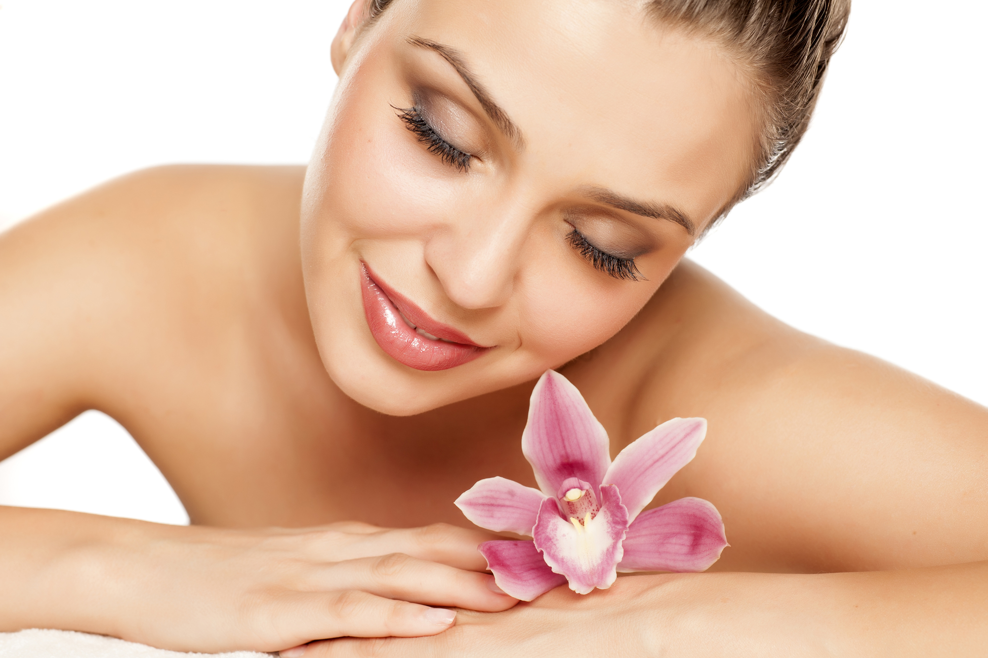 a pretty young woman lying with orchid on a white background Facial Waxing Hendersonville TN